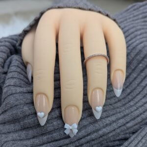 Neutral French tips with 3D heart and bow accents for a sweet, minimal aesthetic.